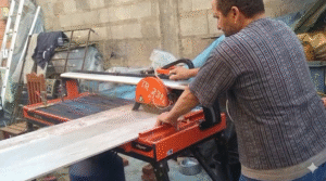 Profissional cortando porcelanato em máquina própria, garantindo precisão no acabamento da obra.