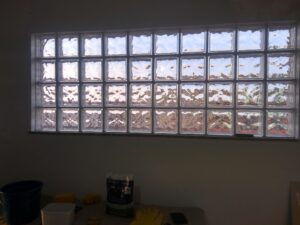 Janela feita com blocos de vidro instalada em parede interna durante obra de construção.